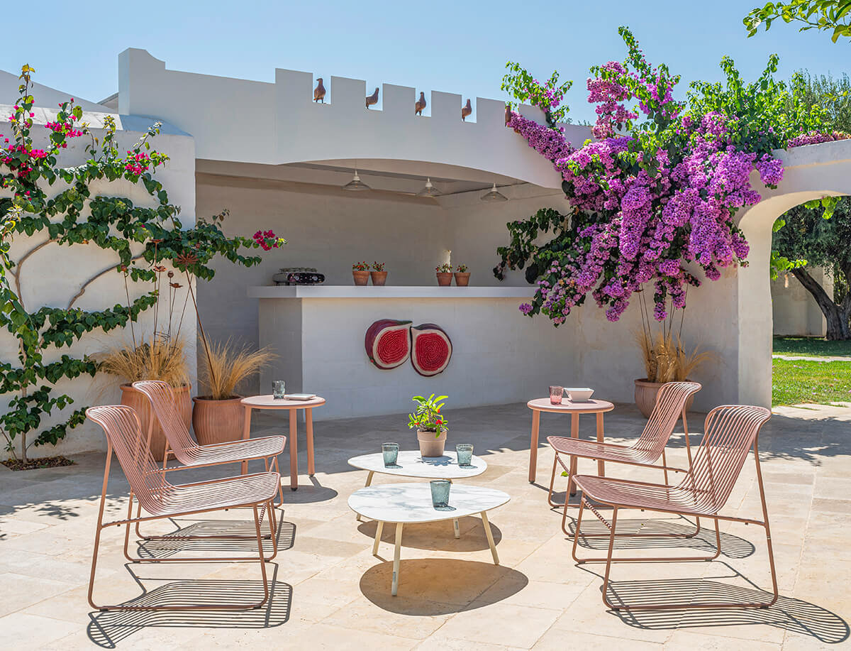 Salon de jardin EMU Riviera, fauteuils et tables filaires terracotta sous une pergola fleurie de bougainvillier