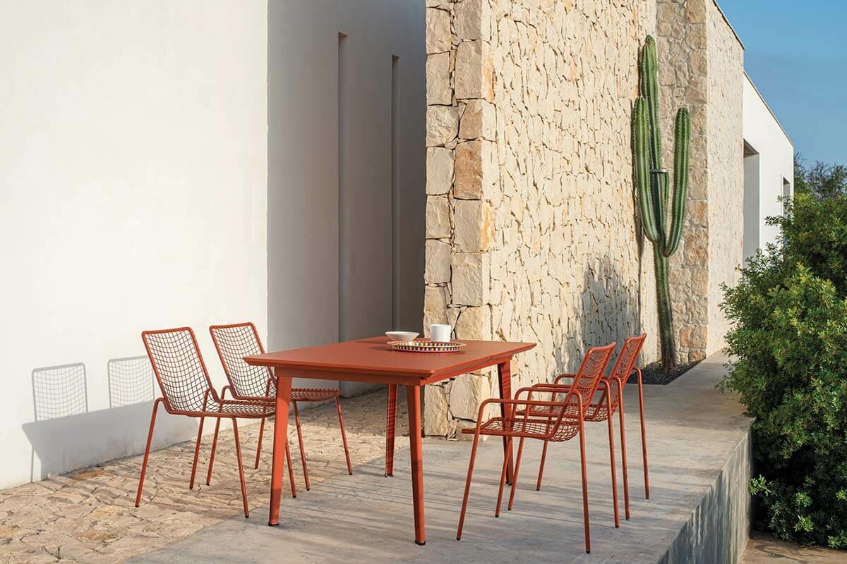 Table EMU Plus et chaises filaires terracotta sur une terrasse minérale avec cactus