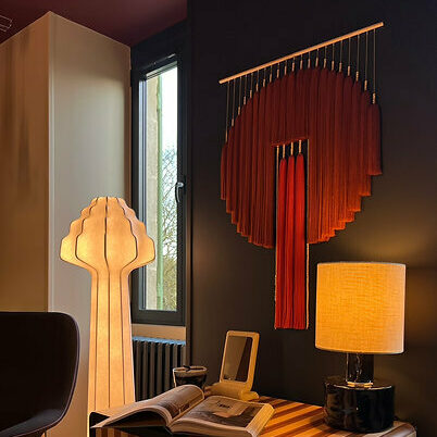 Tenture murale en tissu rouge de Romy Bret et lampe sculpturale en bois dans un intérieur bohème